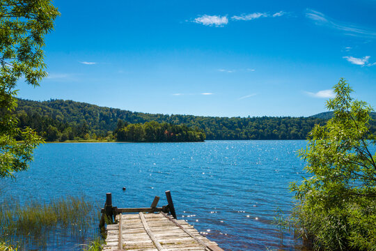 Wooden Pier Extending into a Scenic Mountain Lake Under a Clear Blue Sky