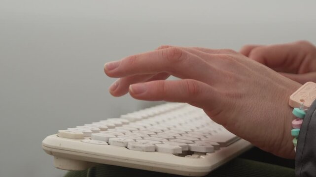 Typing keyboard hands typing on a white wireless keyboard in a close up shot for office or remote work context