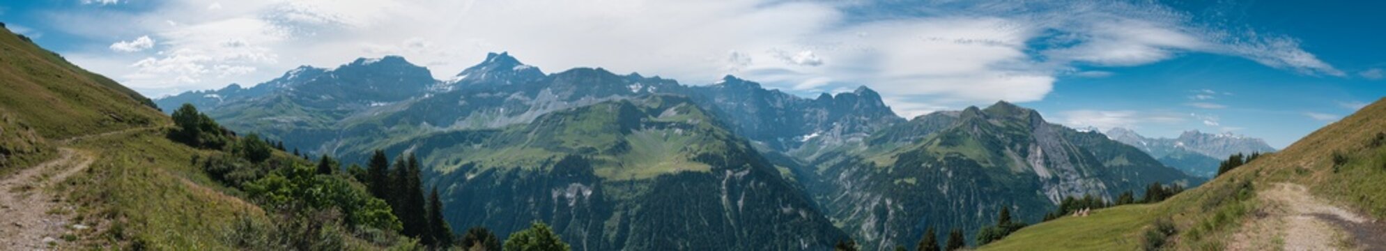 Large panorama of the Sch&auml;chen Valley in the canton of Uri in summer with a blue sky and white clouds.