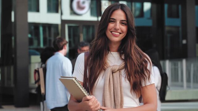 Student girl smiling at camera standing in front University building on campus at college