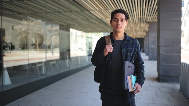 Portrait of smiling hispanic university student standing on college campus hallway