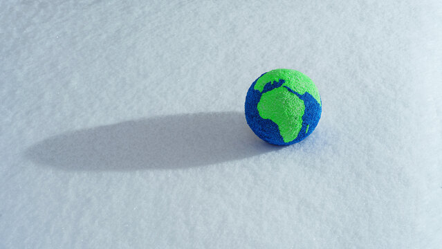 A small green globe lies on the snow in winter. Little Ice Age.