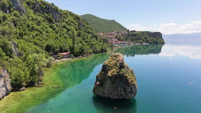 Drone flies close past a rock at Trpejca Beachfront on the shore of Lake Ohrid.
