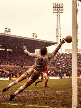 Vintage Muddy Soccer Goalkeeper Diving for a Save in Rain