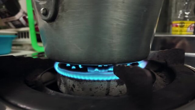Flame of gas stove under old metal pot cooking and boiling water on stove
