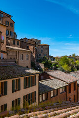 Fototapeta premium Sunlit view across Siena’s rooftops toward a prominent cathedral and historic buildings. The image captures the layered skyline of the old Tuscan city.