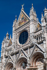 Fototapeta premium Close-up of Siena Cathedral’s intricate facade with rose window and decorative stonework. The image showcases the richness of medieval religious architecture.