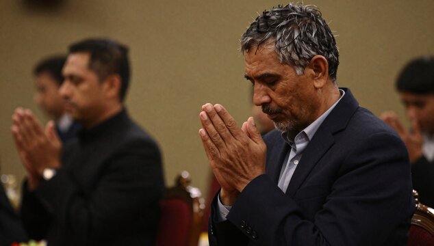 Man in a suit prays with his hands pressed together during a meeting or conference
