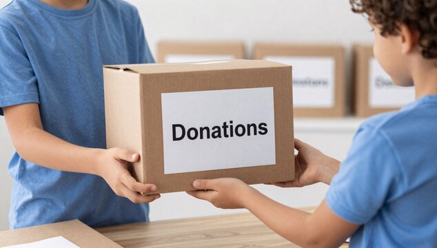 Two children exchange a box labeled donations in front of other cardboard boxes