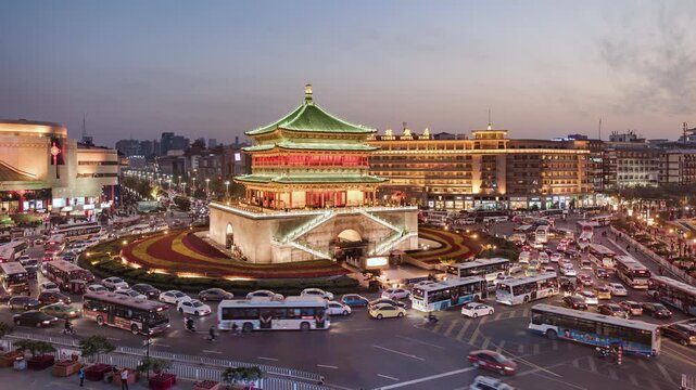 Asia, China, Xian, day to night transition zoom in cityscape time Lapse of Xian Bell tower situated in middle of busy road intersection, with rush hour traffic and commuters at night