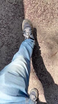 Pasos persona transe&uacute;nte caminando por la calle y andar con zapatillas y vaqueros trayecto zancada, paseo, pierna, pies, tranco, suelo y sombra andando r&aacute;pido en caminata por asfalto carretera 