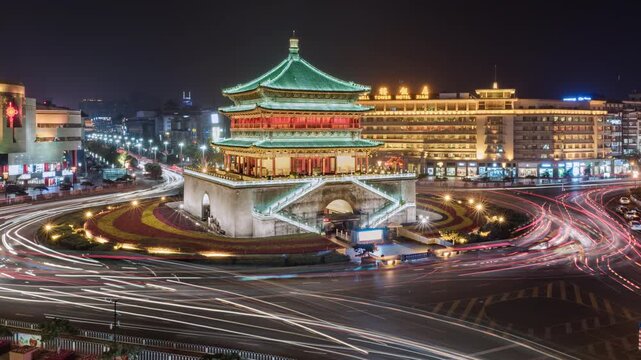  Asia, China, Xian, zoom out cityscape time Lapse of Xian skyline and Bell tower situated in middle of busy road intersection, with rush hour traffic and commuters at night