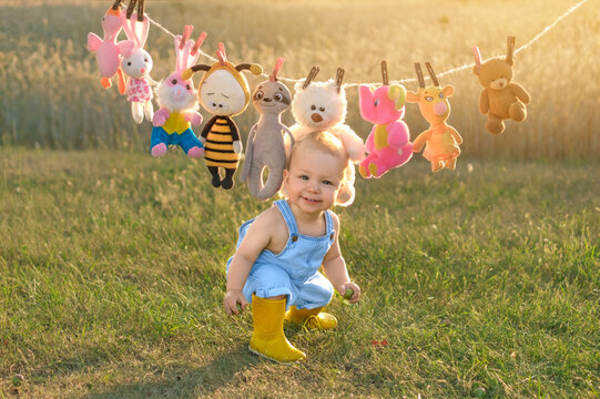 A funny laughing boy is depicted against the backdrop of a pile of stuffed animals hanging from a clothesline.