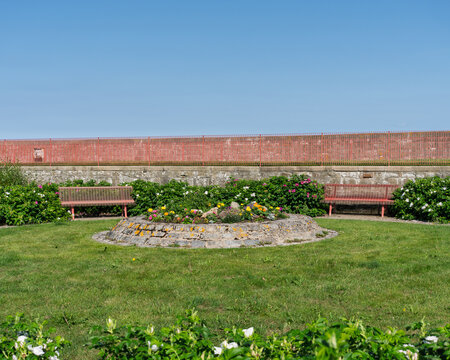 Serene Lossiemouth park showcasing a circular flower bed, green lawns, and inviting red benches in Moray, Scotland