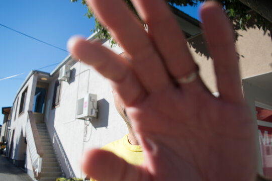 Person covering camera with hand to protect privacy and refuse photography