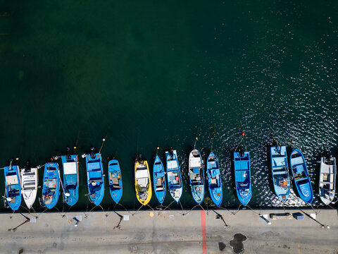 Aerial top down view of small fishing boats moored at the pier in harbor