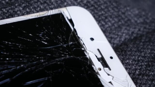 Broken cracked smartphone screen Phone red on dark fabric background, shattered glass display damage concept