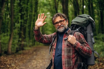 Greetings, hello hand gesture. Hiking experience, senior man is in the forest at daytime © standret