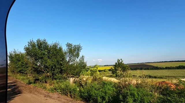 View from window of moving car on picturesque summer landscape of countryside. Automobile riding on quiet country road with beautiful nature scene at sunny day. Slow motion