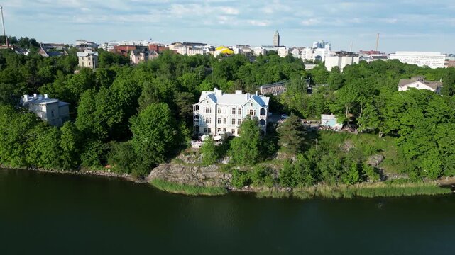 Aerial drone view of Art Cafe Terrace located by T&ouml;&ouml;l&ouml;nlahti Bay in Helsinki, Finland. Beautiful urban waterfront scenery featuring the caf&eacute; terrace, surrounding nature, and Finnish cityscape content.