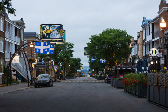 Quebec City, Qu&eacute;bec, Canada, June 27, 2026 -  Cartier street seen at dawn with its series of shops and restaurants, signature giant lampshades and Quebec fleur de lys flags 