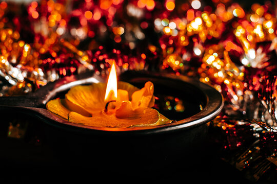 Golden Diwali Diya lamp with flame, floating in a pool of golden tinsel for traditional festival decoration