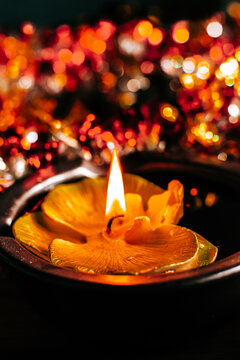 Golden Diwali Diya lamp with flame, floating in a pool of golden tinsel for traditional festival decoration