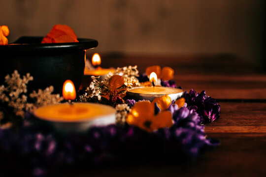 Warm tea light candles burning in a floral arrangement with purple and orange flowers for Diwali festival decoration