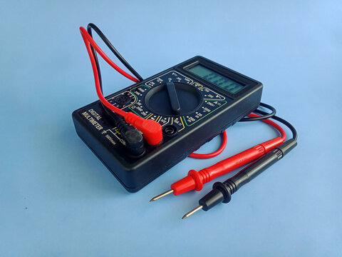 Electronic digital multimeter with probes on blue background