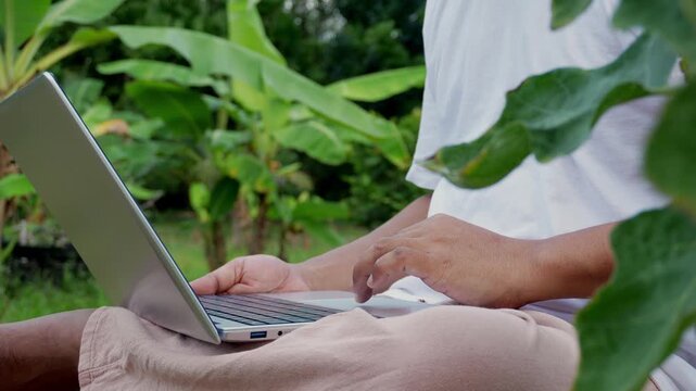 Remote work in a peaceful garden with laptop, young professional enjoying flexible outdoor workspace, maintaining productivity and healthy work life balance