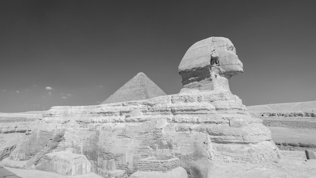 The Sphinx at the Giza plateau, Cairo, Egypt, with the Cheops pyramid (also known as the Great Pyramid) on the background. Black and white.
