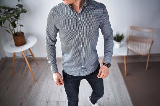 Man in checked shirt walking in modern living room with plants