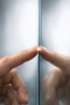A person's hands touch a mirror, creating a sense of introspection and self-reflection