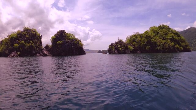 slow motion still view of horizontal pane view look out to shallow blue green turquoise peaceful lagoon from a small boat to mountains and coral rocks at small fishing village of Siete Pecados Marine 