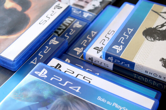 PlayStation 4 and PS5 video games in a close-up view. Overlapping physical blue disc cases creating a geometric design pattern for modern gaming entertainment and virtual worlds.