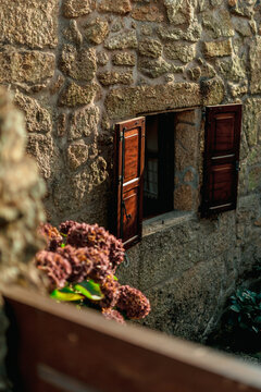 Rustic Stone House Window with Wooden Shutters and Green Hedge, Rural Spain