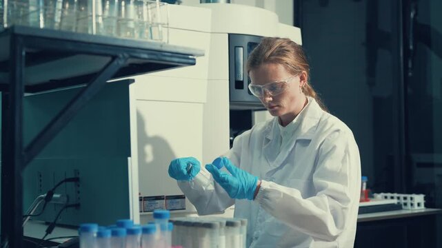 Female scientist loading test tubes into a centrifuge machine during a scientific experiment in a modern research laboratory