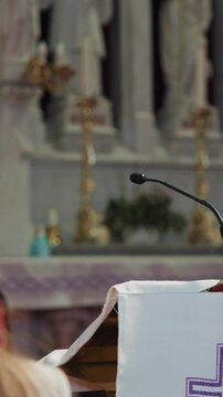 Woman lector in the Catholic Church, standing behind the pulpit and reading Scripture on a microphone, to the congregation at Mass.