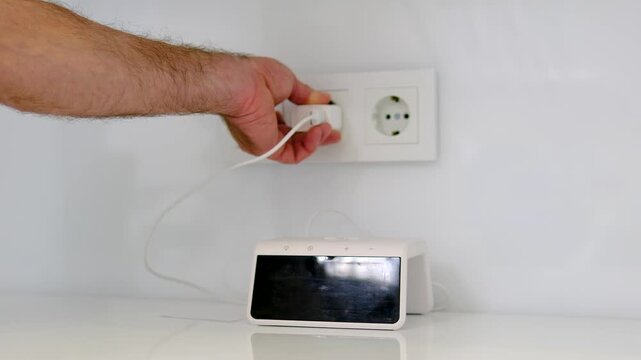 Male hand unplugging digital clock showing 7 42 from double wall outlet in home interior saving electricity close up everyday routine video
