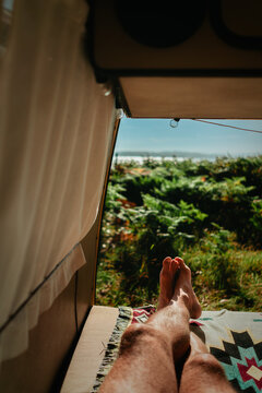 Cozy Van Life POV &ndash; Couple's Legs Resting in Open Campervan with Forest and Sea View