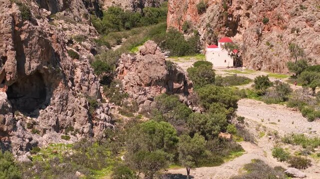 Agiofarango canyon church with red dome Crete Greece. Drone close up view of cave and  Agios Antonios chapel  orange cliffs in wild rocky gorge. Scenic landscape, 4k.