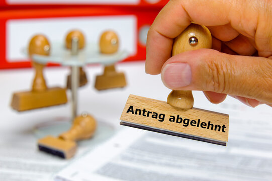 Ein Holzstempel in der Hand mit Aufschrift - Antrag abgelehnt