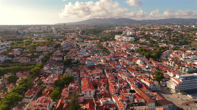 A drone flies forward above a cluster of terracotta rooftops in a historic old town