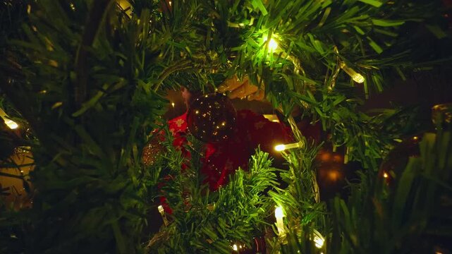Creative View From Inside a Decorated Christmas Tree Framing a Young Woman Decorating Holiday Ornaments With Warm Fairy Lights and Cozy Fireplace Reflections