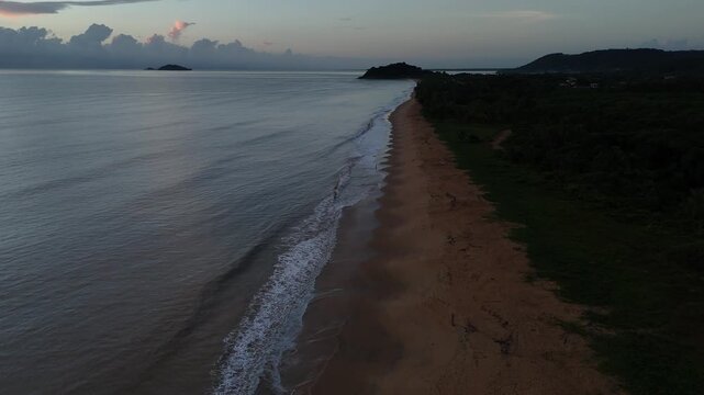 Morning drone flight over a tropical beach with gentle waves and calm Atlantic Ocean in French Guiana.