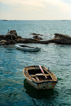 Two Rustic Wooden Fishing Boats Moored on Rocks by Calm Atlantic Sea
