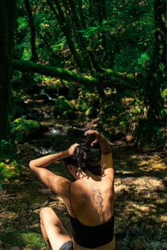 Woman Sitting by Mossy Forest Stream &ndash; Peaceful Nature Retreat in Green Woods