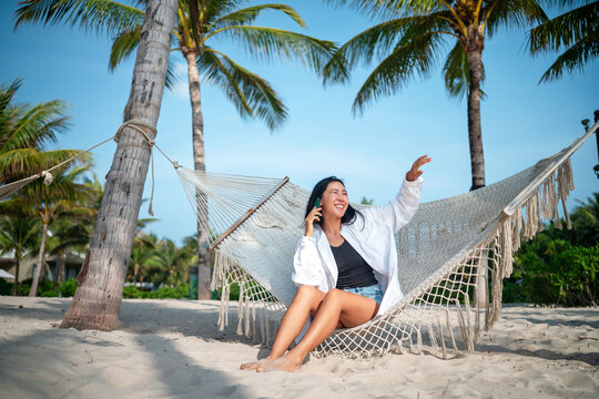 Asian woman embracing freedom at the beach, enjoying travel, self-expression, and digital connection