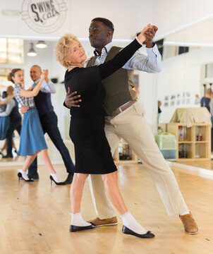 Man and senior woman dancing waltz in studio