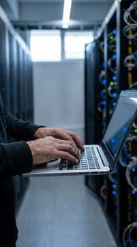 Technician typing on a laptop at a workstation cart in a data center server aisle